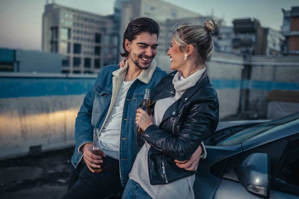 Frau und Mann feiern den Autoverkauf mit einem Bier.